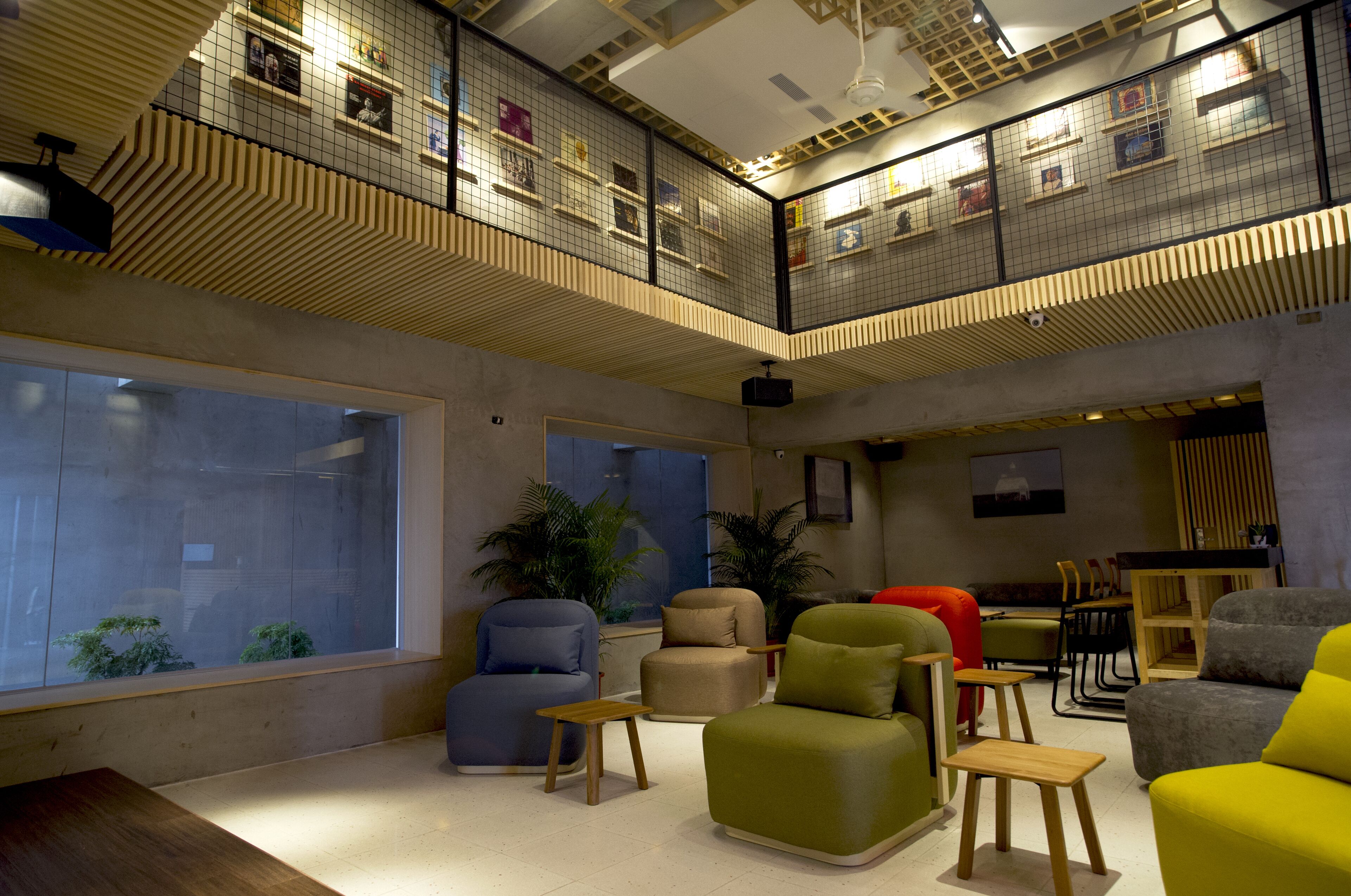 A spacious lounge area with multiple seating options, large windows, and a mezzanine level with a grid-like ceiling design.
