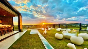 A rooftop terrace with a bar area, seating, and a view of the sunset. - FFF Hotel (Hengchun)