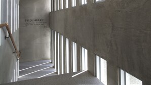 A corridor with concrete walls and large windows. - FFF Hotel (Hengchun)