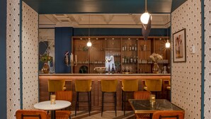 A bar area with wooden shelves, bar stools, and a bar counter. - Work From Here at Bristol Hotel (Avignon)