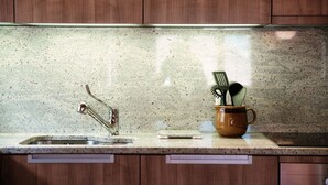 Een keuken met een granieten aanrecht, een roestvrijstalen spoelbak, houten kastjes en een koffiemok met bestek.
