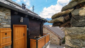 Een houten chalet met een stenen gevel, een houten deur en een klein balkon.