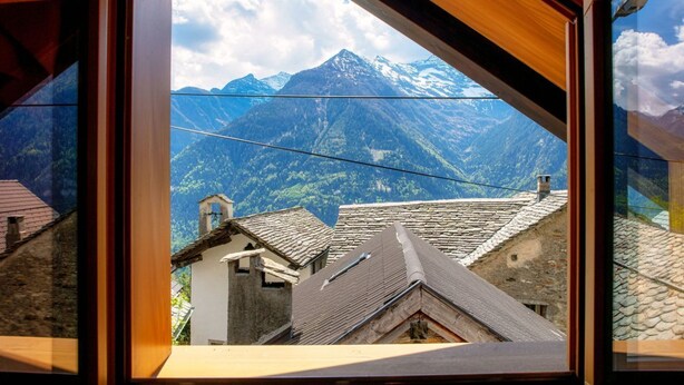 Bergzicht door een raam met traditionele architectuur.