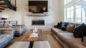 A modern living room with a fireplace, a large flat-screen TV, a sofa, and a coffee table. - Luxury Townhome: Hot Tub, Golf, Skiing! Easy Access to Frostwood Gondola (Park City)