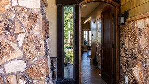 A stone-walled hallway with a wooden door and a view of greenery outside. - Luxury Townhome: Hot Tub, Golf, Skiing! Easy Access to Frostwood Gondola (Park City)