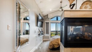 A bedroom with a large mirror, a TV, a fireplace, and a view of the outdoors. - Luxury Townhome: Hot Tub, Golf, Skiing! Easy Access to Frostwood Gondola (Park City)