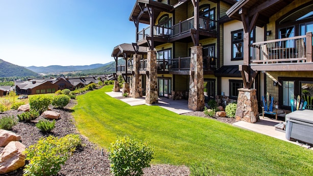 A multi-story building with a stone foundation, large windows, and a well-maintained lawn. - Luxury Townhome: Hot Tub, Golf, Skiing! Easy Access to Frostwood Gondola (Park City)