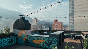 Eine Dachterrasse mit Grill, Sitzgelegenheit und Lichterketten.