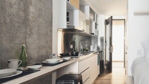 Eine moderne Küche mit einer langen Arbeitsplatte, Edelstahlgeräten und Blick in das angrenzende Schlafzimmer.