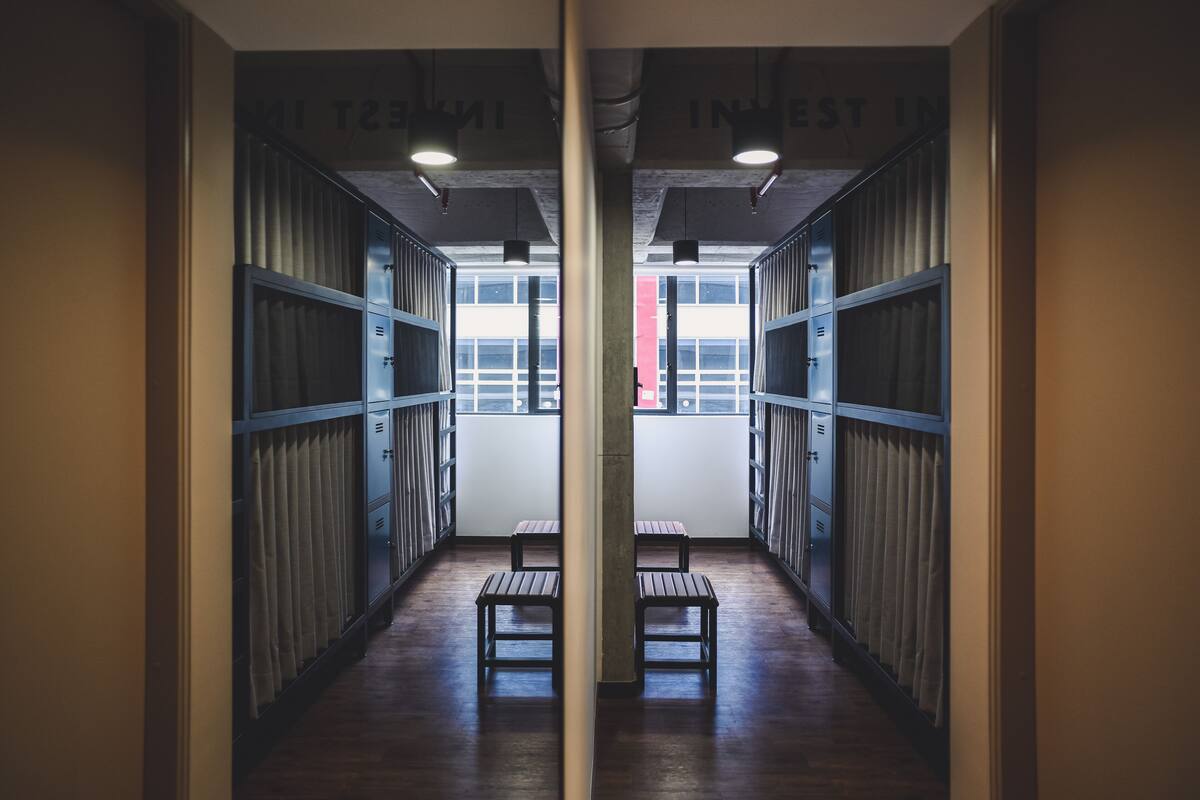 A corridor with lockers, benches, and a view of the outside.