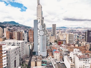 A high-rise building with a unique architectural design, surrounded by a dense urban area with various other buildings. - Spotty Hotels (Bogotá)
