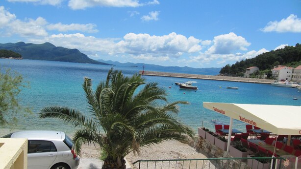 Blick auf die Küste mit Strand, Booten und einem Restaurant mit Außenbereich.