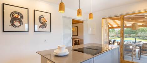 Une cuisine moderne dotée d’un îlot central, de luminaires suspendus et d’œuvres d’art encadrées accrochées au mur.