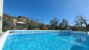 A rectangular swimming pool with clear blue water, surrounded by trees and a building. - MINERVA HOLIDAYHOME - MIMOSA APARTMENT (Manerba del Garda)