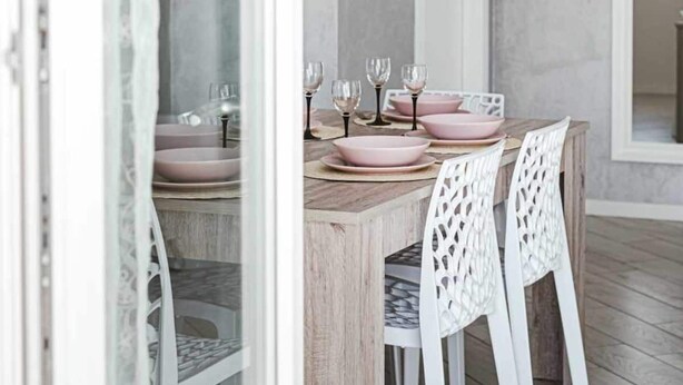 A dining area with a wooden table, pink bowls, and white chairs. - MINERVA HOLIDAYHOME - MIMOSA APARTMENT (Manerba del Garda)