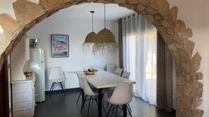 A dining area with a stone archway, a white table, and chairs. There is a hanging light fixture above the table. - Villa Pals very beautiful sea view and Medes islands, private swimming pool (Pals - Masos de Pals)