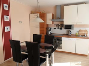 A compact kitchen with a dining area, featuring a stove, microwave, and basic appliances.