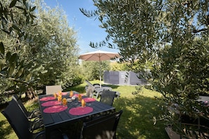 An outdoor dining area with a table set for four, surrounded by olive trees.