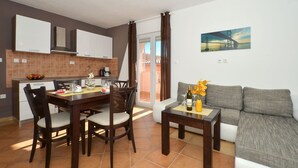 Een moderne keuken met donkerhouten kasten, een eettafel met stoelen en een grijze bank met een kleine tafel ernaast.