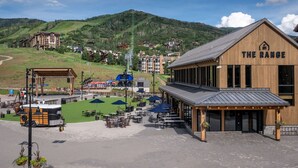 A wooden building with "THE RANGE" sign, outdoor seating, and a view of a mountain.