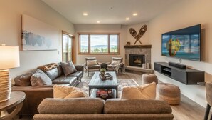 A spacious living room with a fireplace, comfortable seating, and a large window offering a view.