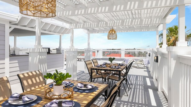 Eine Terrasse im Freien mit weißen Geländern, gedeckten Tischen und hängenden Korblampen.