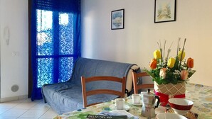 Una habitación acogedora con una cama, una mesa de comedor dispuesta con una cafetera, tazas y un florero.