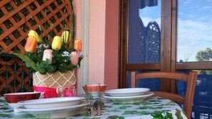 Una mesa dispuesta con platos blancos, una copa y un florero con tulipanes amarillos y rosados.