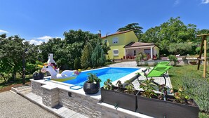 A swimming pool with a unicorn float, a stone wall, and a house in the background. - House 2065/32772 (Istria - Žminj), 20000m from the beach (Žminj)