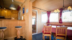 Een houten interieur met een keuken, een eethoek en een raam met gordijnen.