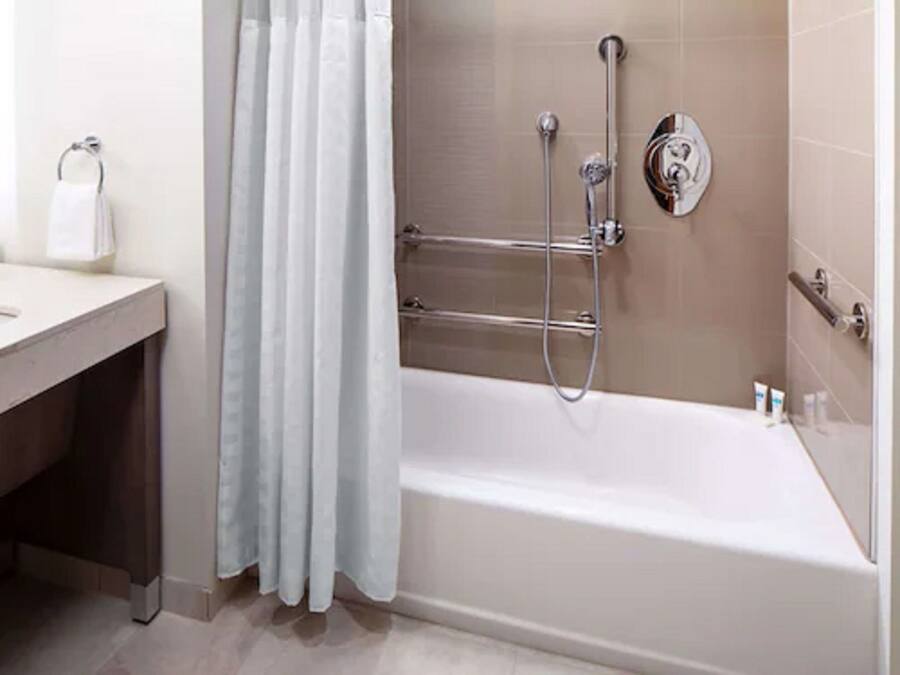 A modern bathroom with a bathtub, shower, and a towel rack.