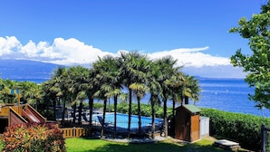 A pool area with a slide, surrounded by palm trees and a view of the sea.