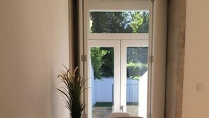 Ein Essbereich mit Tisch und Stühlen, einer Topfpflanze und Blick ins Freie durch eine Glastür.