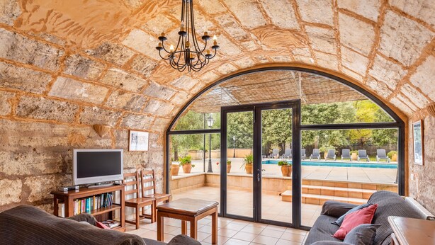 A stone-walled room with a television, books, and a sofa. - Holiday Home “Sa Mina” with Garden, Pool, Terraces, Air Conditioning & WiFi (Selva)