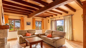 A living room with two sofas, a coffee table, wooden beams on the ceiling, and large windows with curtains. - Holiday Home “Sa Mina” with Garden, Pool, Terraces, Air Conditioning & WiFi (Selva)