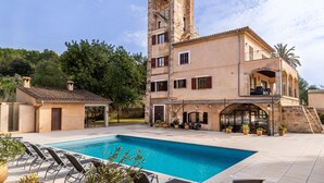 A building with a swimming pool, outdoor seating, and a tower structure. - Holiday Home “Sa Mina” with Garden, Pool, Terraces, Air Conditioning & WiFi (Selva)