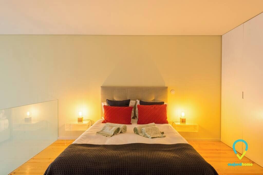 A modern bedroom with a large bed, two bedside tables with lamps, and a neutral color scheme.