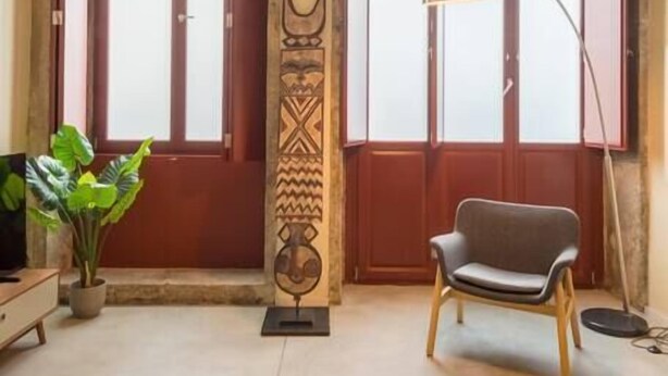Une pièce comprenant une chaise en bois, un lampadaire et un panneau décoratif mural.
