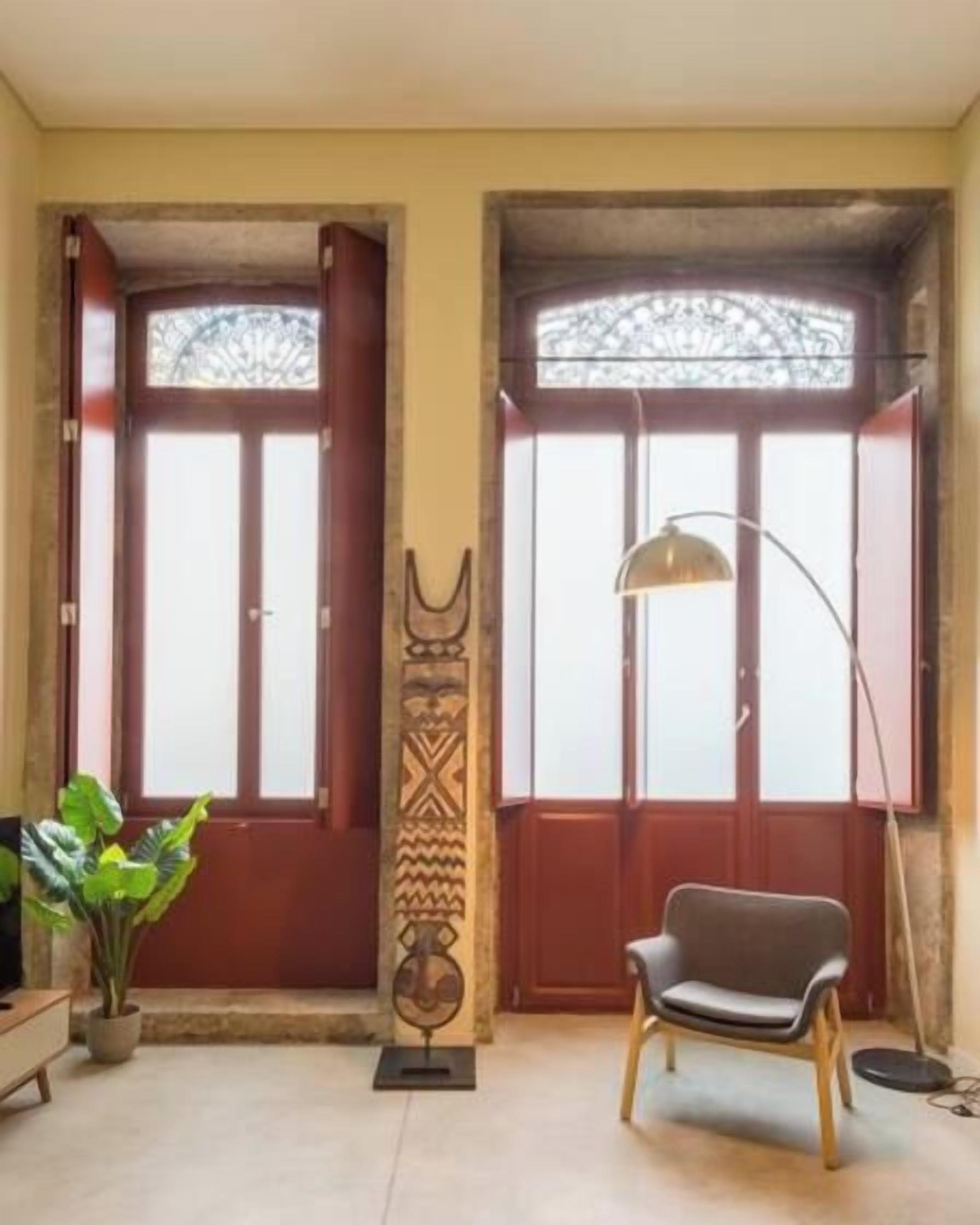 A room with a wooden chair, a floor lamp, and a decorative wall panel.