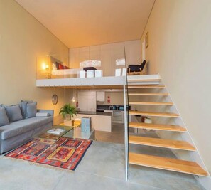 A modern apartment with a living area, a kitchen, and a staircase.