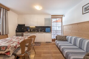 A compact living space with a kitchenette, a dining area with a table and chairs, and a sofa.