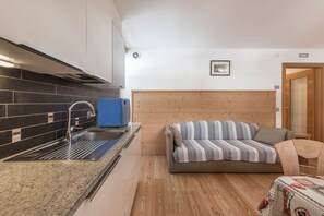 A compact kitchen with a modern sink and a wooden headboard in the living area.
