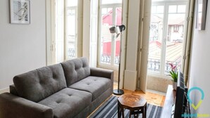 Una sala de estar con un sofá gris, una lámpara de pie y una pequeña mesa de madera.