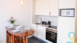 Una cocina compacta con armarios blancos, microondas, estufa y lavabo.