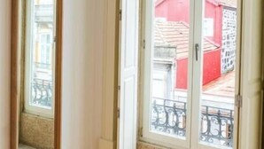 Una habitación con piso de madera, una puerta blanca y una ventana que ofrece vistas a edificios.
