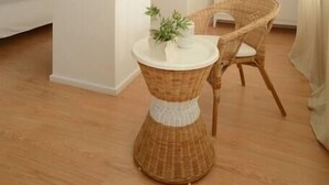 A modern, minimalist room with a wicker table and chair, a white cabinet, and a bed in the background. - SOFTLY PORTO - Lovely apartment right the heart of city (Porto)