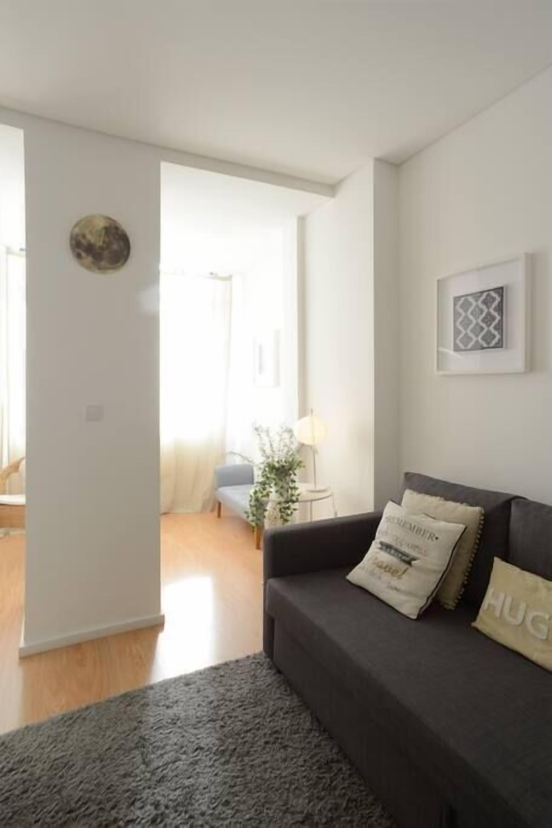 Una sala de estar moderna con un sofá oscuro, una alfombra y un cuadro en la pared.