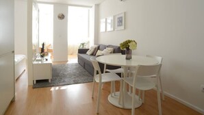 A modern living space with a dining area, a sofa, and a small table with a vase of flowers. - SOFTLY PORTO - Lovely apartment right the heart of city (Porto)