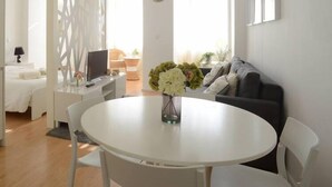 A modern living room with a round white table, a grey sofa, and a TV on a white cabinet. - SOFTLY PORTO - Lovely apartment right the heart of city (Porto)