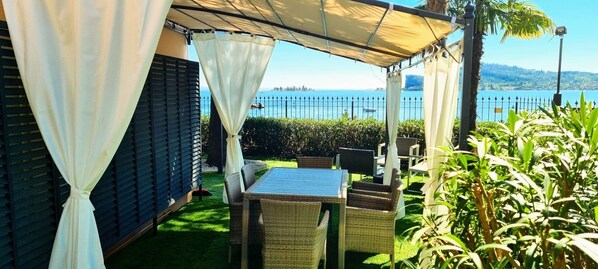 A patio with wicker furniture, a table, and a view of the sea.